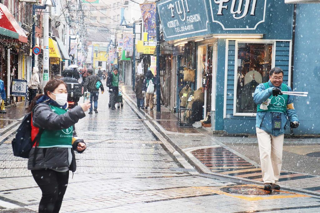 雪の中!ドブ板通りをPRしながら清掃活動